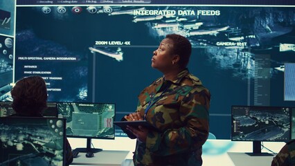 Woman high tech specialist studying satellite CCTV visualization on a big screen, preparing troops...