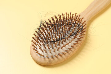 Wooden brush with lost hair on yellow background