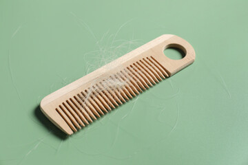 Wooden comb with lost hair on green background