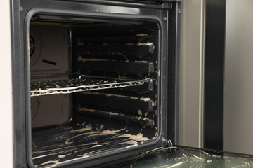 Obraz premium Open electric oven covered with cleaning foam in kitchen