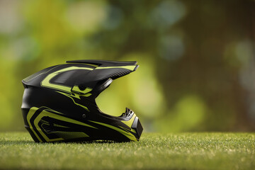 Modern motorcycle helmet with visor on green grass, space for text