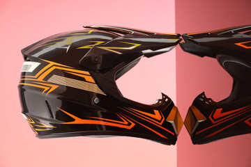 Modern motorcycle helmet with visor on mirror surface against pink background
