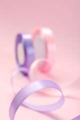 Ribbon reels in different colors on pink background, closeup view