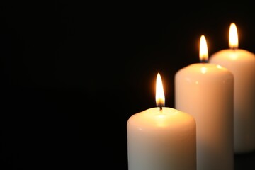 Many burning candles on black background, closeup. Space for text