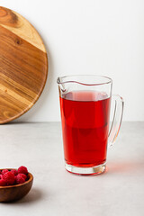 Red color drink in the glass jug on gray background.