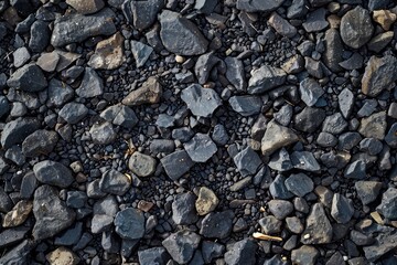 A close up of black rocks with a dark, moody atmosphere. The rocks are scattered and uneven, giving the impression of a rough, untamed landscape