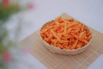 Crispy Corn Puffs in rattan basket on bamboo mat. Selective focus.