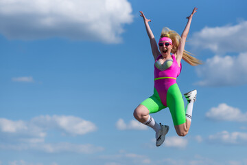Young beautiful blonde woman in sports shorts, a pink bodysuit and pink sunglasses is doing sports outdoors. Jumping against the sky. Sports, Active lifestyle, sports training, healthy lifestyle