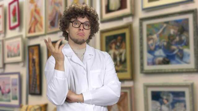 Young guy standing in the art gallery and thinking. Art criticism concept.