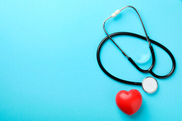Stethoscope and red heart on light blue background, top view. Space for text