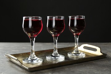 Delicious cherry liqueur in glasses on grey table