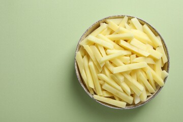 Fresh raw potatoes in bowl on green background, top view. Space for text