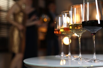 Different tasty wines in glasses on white table indoors, selective focus