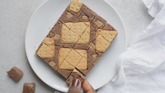 Overhead view of chocolate fudge with cookies and fudge pieces on a white plate, Top view of hazelnut chocolate fudge cut into pieces, fudge cookie candy on a white granite countertop