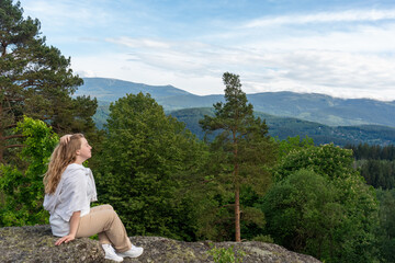 woman sits on a rock overlooking the mountains. Hiking in the mountains and solo travel. Rest and relaxation. Mocap. High quality photo