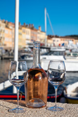 Obraz premium Glasses of cold rose Cote de Provence wine in old fisherman boats and yacht harbour in Saint-Tropez, summer vacation on French Riviera in Provence, France