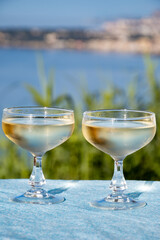 Sparkling wine, cava or champagne in two coupe glasses on table with view on blue sea, Menton and Monte-Carlo, French Riviera, France is summer