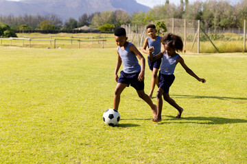 Obraz premium Happy african american schoolchildren playing football on field at school