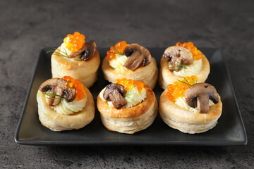 Delicious puff pastry with cream cheese, red caviar, mushrooms and dill on grey table