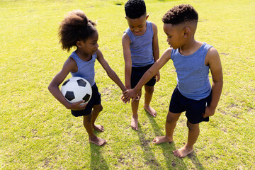 Obraz premium Happy african american schoolchildren playing football on field at school