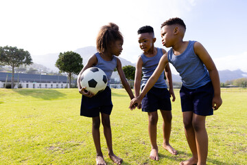 Obraz premium Happy african american schoolchildren playing football on field at school