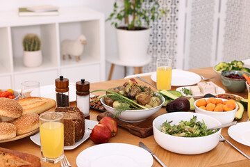 Healthy vegetarian food, glasses of juice, cutlery and plates on wooden table indoors