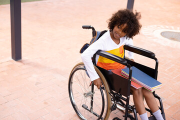 Happy african american schoolgirl in wheelchair at school