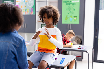 Obraz premium Happy diverse schoolchildren using sign language in school classroom