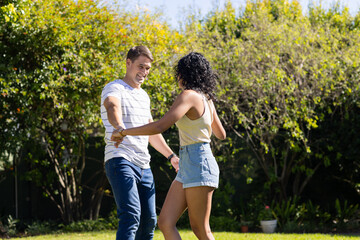 Dancing together, young couple enjoying time outdoors in garden