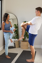 Practicing yoga, young couple balancing on one leg on yoga mats indoors