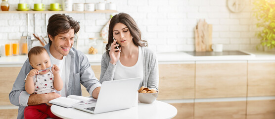 A young family is working from home in their kitchen. The mother is on the phone while the father...