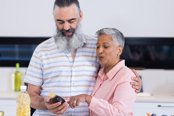 Senior couple reading food label together in kitchen, making healthy choices