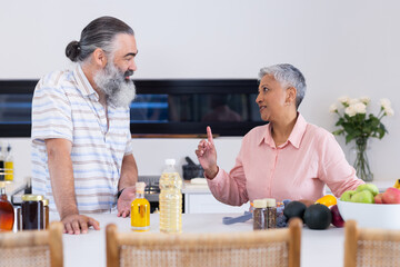 Senior couple discussing healthy cooking in modern kitchen with fresh produce