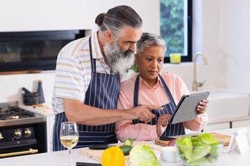 Cooking together, senior couple using tablet for recipe in modern kitchen