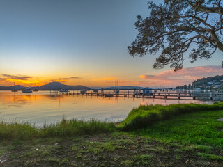 Fototapeta premium Sunrise over the calm water with boats and reflections