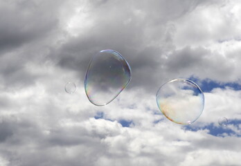 multicolored floating soap bubbles in the cloudy sky, hope concept. two big bubbles of soap to entertain childs