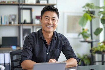 Portrait of confident smiling Asian man sitting at desk