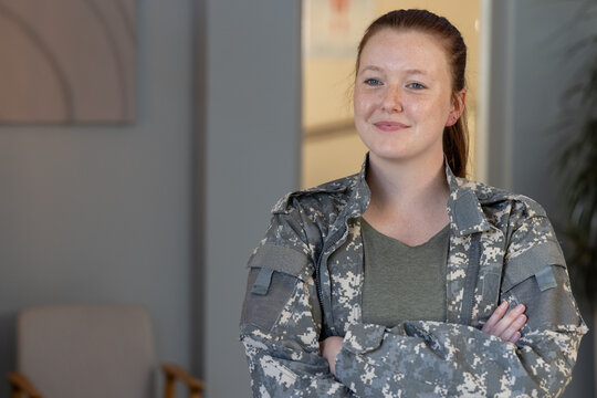 Smiling woman in undefined uniform standing with arms crossed in office, copy space