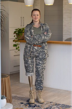 Woman in undefined uniform standing confidently with prosthetic leg in modern room