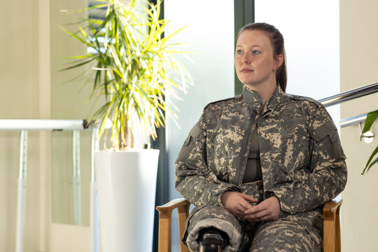 Sitting in chair, woman in undefined uniform with prosthetic leg in bright room, copy space