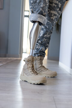 Military soldier personnel with prosthetic leg wearing camouflage pants and boots indoors