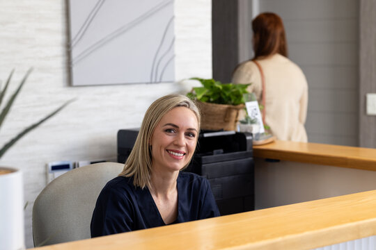 Welcoming patients, smiling receptionist at medical clinic front desk