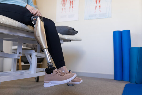 Sitting on medical bench, person with prosthetic leg in rehabilitation center, copy space - Powered by Adobe