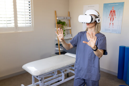Wearing VR headset, medical professional in scrubs exploring virtual environment in medical clinic, 