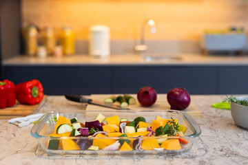 Preparing vegetables in kitchen, glass dish with chopped vegetables on countertop, copy space