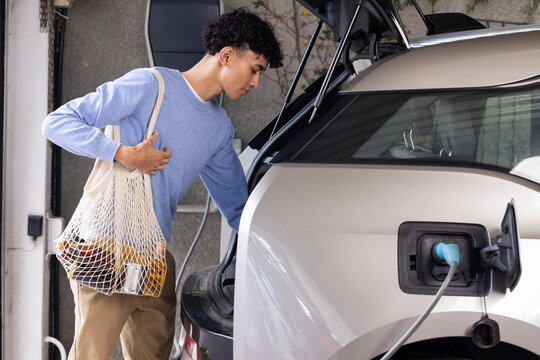 Unloading groceries from car while charging electric car car vehicle in garage