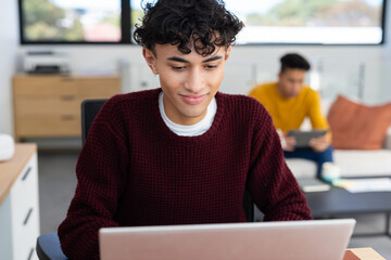 Using laptop, young man working while partner uses tablet in background
