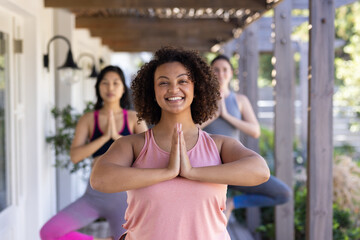 Practicing yoga, three women friends in outdoor class, smiling and enjoying exercise
