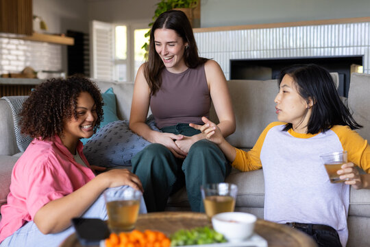 Relaxing at home, three women friends enjoying drinks and conversation on couch - Powered by Adobe