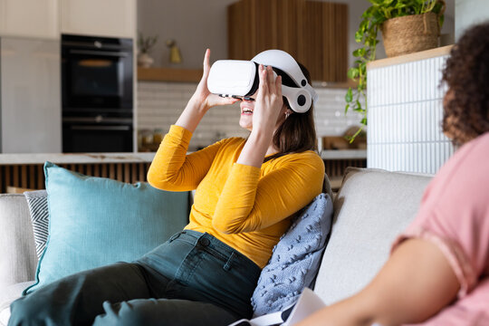 Using VR headset, woman sitting on couch and enjoying virtual reality experience